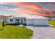 Charming single Gathering home with well-kept lawn, brick driveway, and modern architectural design against a colorful sky at 7407 S Blue Sage, Punta Gorda, FL 33955