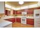 Bright kitchen featuring cherry cabinets, white appliances, and plenty of counter space at 7941 Pineglen Ct # 37, Sarasota, FL 34238