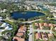 An aerial view of a community with lush greenery, mature trees, and a picturesque pond at 904 Harbor Town Dr, Venice, FL 34292