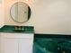 A luxurious bathroom featuring green marble countertops, cabinets and a jetted tub at 919 Key Way, Nokomis, FL 34275