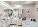 Bright bathroom featuring double sinks, white cabinets, large mirror and soaking tub at 951 Sea Fox Rd, Venice, FL 34293