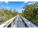 A wooden boardwalk is surrounded by green trees and foliage at 951 Sea Fox Rd, Venice, FL 34293