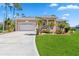 Charming tan home featuring a spacious two-car garage, manicured lawn, and beautifully landscaped front yard at 951 Sea Fox Rd, Venice, FL 34293
