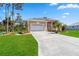 Charming tan home featuring a spacious two-car garage, manicured lawn, and beautifully landscaped front yard at 951 Sea Fox Rd, Venice, FL 34293