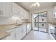Bright kitchen features white cabinetry, granite countertops, stainless steel appliances and sliding glass door to balcony at 990 Bird Bay Way # 258, Venice, FL 34285