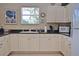 Bright kitchen featuring white cabinets, a garden window, black countertops, and modern appliances at 1000 Gardens Edge Dr # 1023, Venice, FL 34285