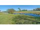 Beautiful backyard view features a tranquil pond, lush green grass, mature trees, and a manicured golf course at 1003 N Gondola Dr, Venice, FL 34293