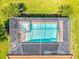Aerial shot of the screened pool and spa area surrounded by lush greenery and tile roofing at 10064 Cozy Grove Dr, Venice, FL 34293
