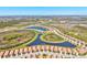 Aerial view of community homes encircling a scenic blue pond and lush green landscaping at 10064 Cozy Grove Dr, Venice, FL 34293