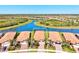 High angle aerial view of home showing tile roof, landscaping, and neighborhood next to winding lake at 10064 Cozy Grove Dr, Venice, FL 34293