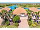Stunning aerial view of a home with a tile roof, two-car garage, and lush landscaping near a scenic lake at 10064 Cozy Grove Dr, Venice, FL 34293