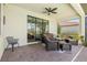 Covered brick patio with cozy furniture and inviting lake view through sliding glass door at 10064 Cozy Grove Dr, Venice, FL 34293