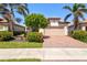 Charming one-story home featuring a two-car garage, brick driveway, and colorful landscaping at 10064 Cozy Grove Dr, Venice, FL 34293