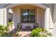 Quaint front porch featuring a cozy seating area with brick flooring and lush greenery at 10064 Cozy Grove Dr, Venice, FL 34293