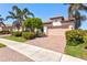 Charming single-story home featuring a brick driveway, lush landscaping, and a two-car garage at 10064 Cozy Grove Dr, Venice, FL 34293