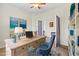 Inviting home office featuring desk, blue chair, stylish decor, and bookshelves at 10064 Cozy Grove Dr, Venice, FL 34293
