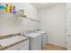 Laundry room with sink, granite countertop, modern washer, dryer and ample shelving at 10064 Cozy Grove Dr, Venice, FL 34293