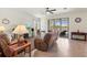 Inviting living room with neutral tile floors, comfortable seating, and views of the lanai and lake at 10064 Cozy Grove Dr, Venice, FL 34293