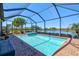 Relaxing screened-in pool area with brick flooring and spa overlooking a serene lake at 10064 Cozy Grove Dr, Venice, FL 34293