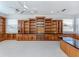 Large bonus room with wall-to-wall light gray carpet, built-in wooden cabinets and shelves and lots of natural light at 101 Portofino Dr, North Venice, FL 34275