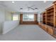 Bright bonus room with light gray carpet, ceiling fan, built-in wooden cabinets and shelves and lots of natural light at 101 Portofino Dr, North Venice, FL 34275