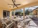 Covered patio with ceiling fan and dining sets overlooking a screened-in pool with waterfall feature and trees in distance at 101 Portofino Dr, North Venice, FL 34275