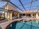 Screened-in pool with a spa, an outdoor kitchen featuring a stainless steel grill and a bar stool swim-up seating area at 101 Portofino Dr, North Venice, FL 34275