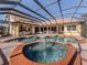 Screened in pool with waterfall feature, hot tub and an outdoor kitchen with stainless steel grill and cabinetry at 101 Portofino Dr, North Venice, FL 34275