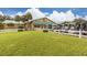 Charming clubhouse exterior with a row of golf carts and white picket fence with lush green lawn at 1041 Capri Isles Blvd # 224, Venice, FL 34292