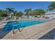 Inviting pool area surrounded by lounge chairs, mature palm trees, and a secure fence, perfect for relaxation at 1041 Capri Isles Blvd # 224, Venice, FL 34292