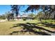 Exterior view of ranch home with a large lawn, mature trees, and stone accents at 1110 Gladstone Blvd, Englewood, FL 34223