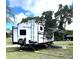 Mesa Ridge Lite RV featuring a ladder, open awning, and hookups in a sunny grassy area at 1110 Gladstone Blvd, Englewood, FL 34223