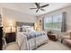 Bedroom features ceiling fan, plush carpeting, and large window with a view of mature trees at 11655 Renaissance Blvd, Venice, FL 34293