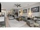 Open living room with a gray sofa and chairs, tile floors, and views into the kitchen at 11655 Renaissance Blvd, Venice, FL 34293