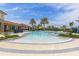 The community pool has a large shallow area, palm trees, a zero-depth entry, and chairs for lounging at 11655 Renaissance Blvd, Venice, FL 34293
