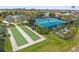 An aerial view displays the tennis court and bocce ball court amenities with lush greenery in the community at 11655 Renaissance Blvd, Venice, FL 34293