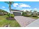 Paver driveway leading to a two-car garage surrounded by lush landscaping at 13032 Oriago St, Venice, FL 34293