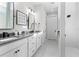 Bright bathroom features double sinks, white cabinetry, black hardware, and a glass enclosed shower at 13251 Borrego St, Venice, FL 34293