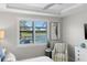 Bedroom featuring a window overlooking a pool and a striped armchair next to a white dresser at 13251 Borrego St, Venice, FL 34293