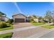 Well-manicured home with a two-car garage, brick-paved driveway, and lush greenery at 13251 Borrego St, Venice, FL 34293