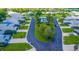 Aerial view of the community featuring a sparkling pool area, manicured lawns, palm trees, and single-story homes at 1400 Colony Pl, Venice, FL 34292