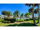Community pool area surrounded by palm trees, lush landscaping, and a white picket fence at 1400 Colony Pl, Venice, FL 34292