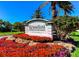 Waterford community sign surrounded by vibrant flower beds and lush landscaping with mature palm trees at 1400 Colony Pl, Venice, FL 34292