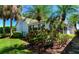 Exterior view of this lovely home featuring lush landscaping, mature palm trees, and a screened-in lanai at 1400 Colony Pl, Venice, FL 34292
