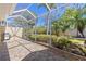 Screened-in patio overlooking the yard with lush landscaping, brick pavers and a stainless steel grill at 1567 Monarch Dr, Venice, FL 34293