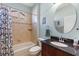 Bathroom with a granite sink and vanity, round mirror, tub and shower combination, and tile flooring at 1567 Monarch Dr, Venice, FL 34293