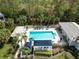 Aerial view of a community pool with lounge chairs, lush landscaping, and a covered patio area at 1567 Monarch Dr, Venice, FL 34293