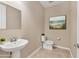 Well-lit half bathroom features tile flooring, a pedestal sink, and an elegant beach-themed art piece at 16258 Hidden Oak Loop, Bradenton, FL 34211