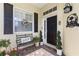 Inviting front porch with a black front door, Welcome mat, and decorative plants and bench at 1627 Lancashire Dr, Venice, FL 34293