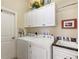 Functional laundry room with washer, dryer, overhead cabinets and utility sink at 1627 Lancashire Dr, Venice, FL 34293